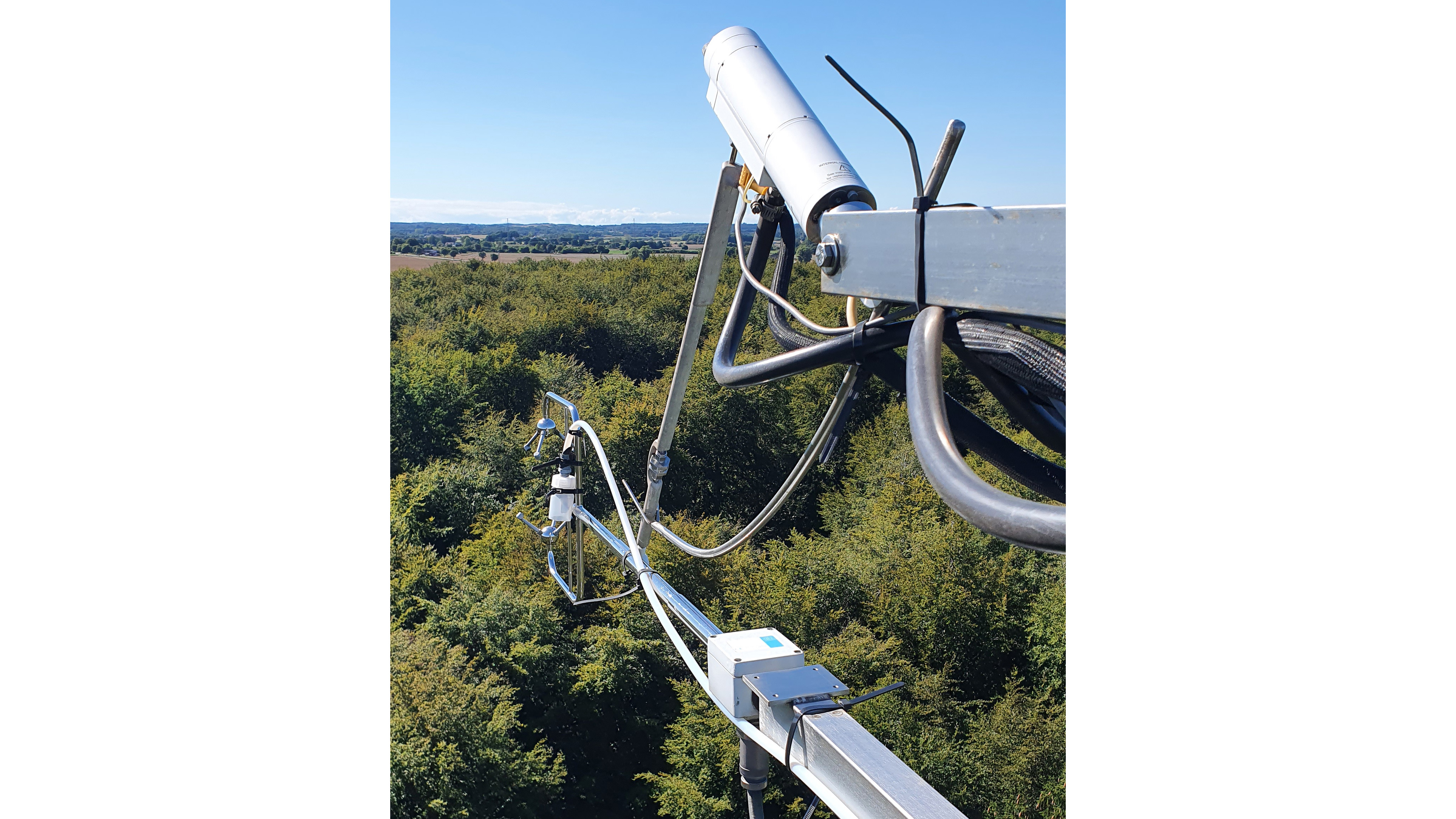 An element of the ICOS observation station with a blue sky and green leafed trees in the background