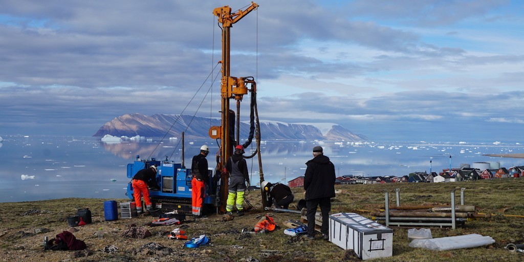 Five people operating a 6 meter tall machine used to take samples from the ground