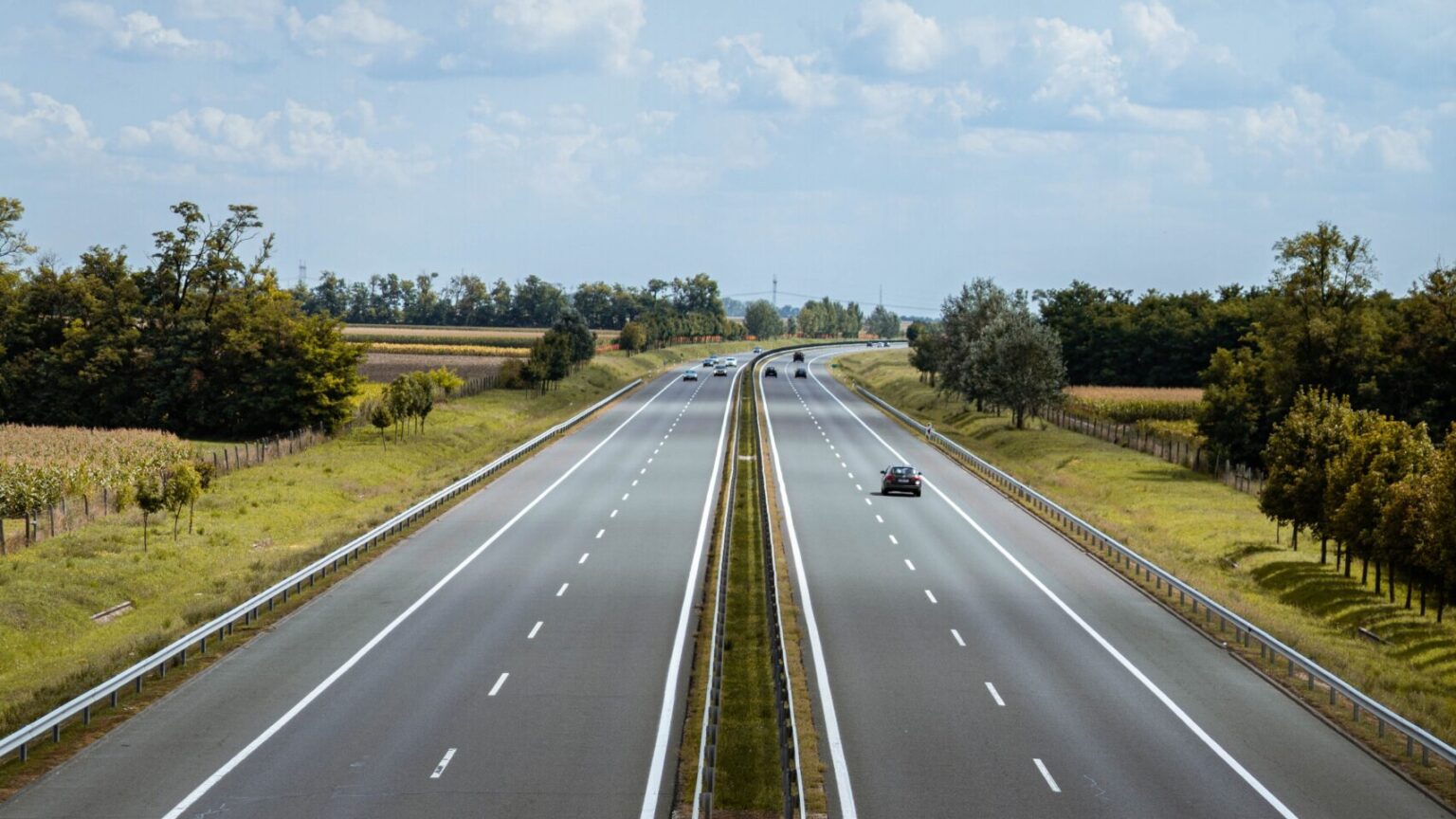 Two highways side by side with a cloudy light blue sky