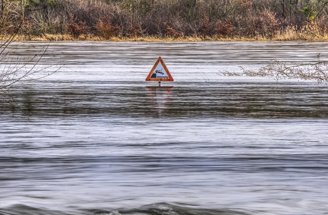Flooded street with street sign poking out of flood water